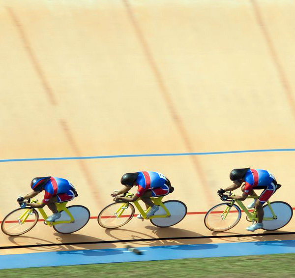 Image of three racers on a wood velodrome with aero helmets and covered rear wheels