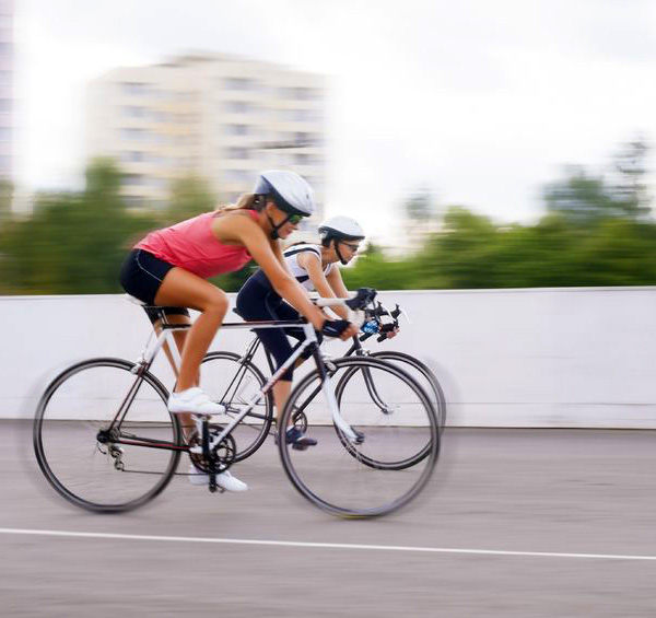 Image of two women riding road bikes through a city