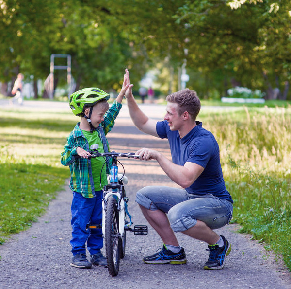 Image of a father and a son high fiving over a childs bike