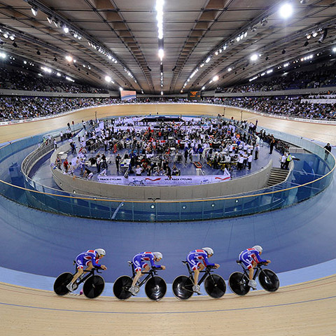 Image of four cyclists pacelining on a wood velodrome in full aero helmets and wheels